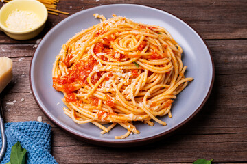 Delicious spaghetti cheese pasta served on a plate Vegetables, Italian tomato sauce and spices arranged on a wooden table, top view
