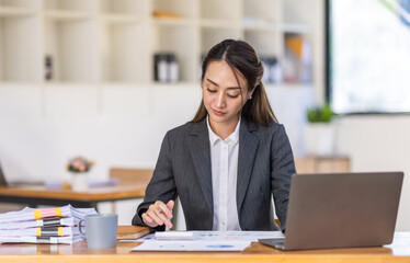 Asian female business analyst financial advisor preparing statistic report studying documents on work desk, Asian business woman work with documents in the office.