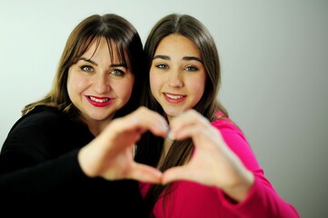 Mom and daughter show heart from hands They look into the frame touching their fingers family...
