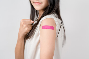 Happy young woman show victory sign after getting a vaccine. showing shoulder with bandage after receiving vaccination, herd immunity, side effect, booster dose, vaccine passport and Coronavirus