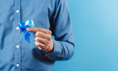 men hands showing Blue ribbon for supporting people living and illness, Colon cancer, Colorectal cancer, Child Abuse awareness, world diabetes day, International Men's Day