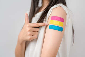 Young woman after getting a vaccine. showing shoulder arm with bandage after receiving vaccination, herd immunity, side effect, booster dose, vaccine passport and Coronavirus pandemic