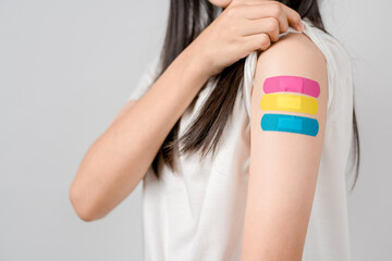 Happy young woman after getting a vaccine. showing shoulder arm with bandage after receiving vaccination, herd immunity, side effect, booster dose, vaccine passport and Coronavirus pandemic