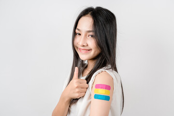 Young woman thumb up sign after getting a vaccine. showing shoulder arm with bandage after...