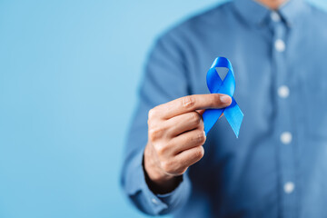 men hands showing Blue ribbon for supporting people living and illness, Colon cancer, Colorectal...