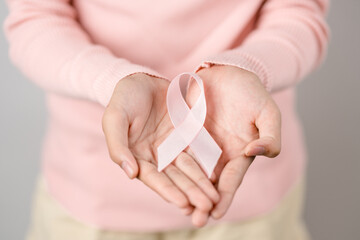 woman hands holding pink ribbon, Breast cancer awareness, world cancer day, national cancer survivor day in february concept...