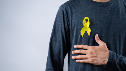 man showing yellow ribbon, september, suicide prevention day, childhood, sarcoma, bone and bladder cancer Awareness month, health care support people and world cancer day concept