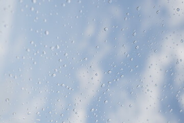빗방울 맺힌 창문 너머로 보이는 파란 하늘과 구름