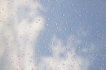 창문에 맺힌 빗방울 너머로 보이는 파란 하늘과 구름