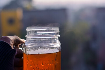 Closeup hand holding a glass jar of morning tea