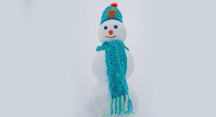 Snowman. Winter clothes, knitted hat and scarf. Snowman isolated on snow background.