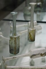 Small pseudo mercury square bottles, tall with long necks, from second or third century AD, displayed on glass archaeology exhibition. Possibly from mediterranean or adriatic region. 