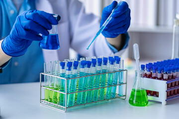 Doctor taking test tube with blue liquid, virologist working in chemical protective suit man studying dangerous virus Biologist at the lab table with a microscope in the laboratory