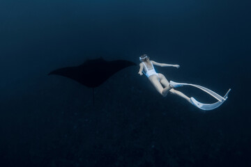 Woman freediver with long white fins swim with manta ray. Freediving with big manta ray