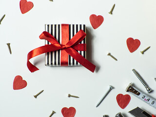 Construction tools and gift on white background with small red hearts and copy space. Construction greeting card for Valentines day. Repair home with love. Gifts for lover. Buying presents for man.