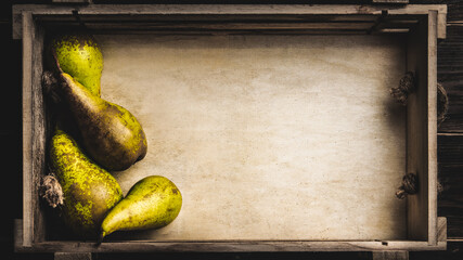 Pears in wooden box on dark wooden table