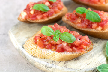 Bruschetta or crostini made with fresh tomatoes, olive oil and basil on a cutting board. Selective focus. Traditional Italian appetizers.