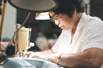 Retriement tailor southeast asian elderly crafting a cloth by sewing machine working at home