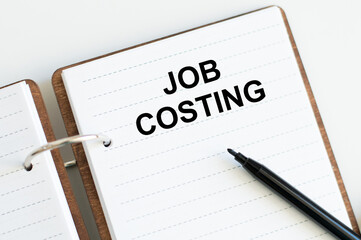 JOB COSTING text on a sticky note on a cork board with pencil ,