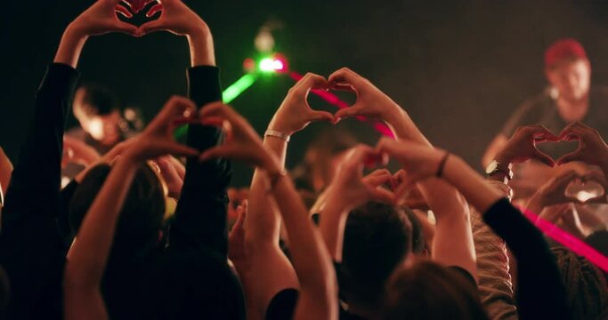 Hands, heart and crowd at a concert, music festival or global youth party with a live band performance at night. Dance, celebration and people in the audience dancing to a love song as fans at event