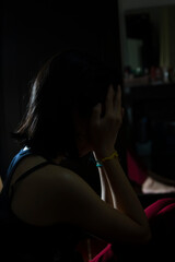 Crying Asian girl in the bedroom, close up view in backlight for Silhouette being alone, sad Asian woman in the dark room, depressed alone, heart broken Asian girl.