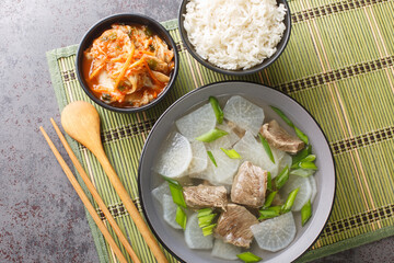 Korean food beef radish soup which is called soegogi muguk served with rice and kimchi closeup on the mat on the table. Horizontal top view from above