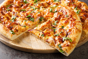 American California pizza with chicken, barbecue sauce, cheese and onions close-up on a wooden board on the table. Horizontal