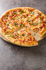 Tasty BBQ Chicken Pizza is a tasty California Pizza with barbecue sauce, cheese and onions closeup on the wooden board on the table. Vertical