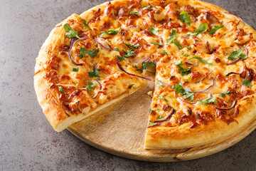 BBQ Chicken Pizza is such a classic with its sweet, tangy, and salty BBQ sauce, bits of juicy chicken, cheese, and savory onions closeup on the wooden board on the table. Horizontal
