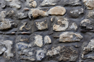 Background texture of wall constructed of irregular shaped dark stones