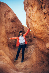 Young happy woman tourist standing in red canyon. Brave female hiker in solo trekking. Adventure, wanderlust, sightseeing. Vertical image.