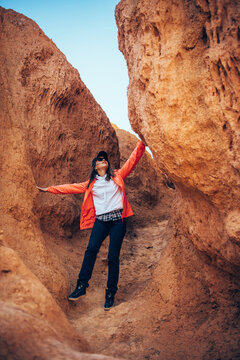 Young happy woman tourist standing in red canyon. Brave female hiker in solo trekking. Adventure, wanderlust, sightseeing. Vertical image.