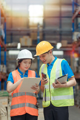 Asian engineer in helmets order and checking goods and supplies on shelves with goods background in warehouse.logistic and business export ,Warehouse worker checking packages on shelf in a large store