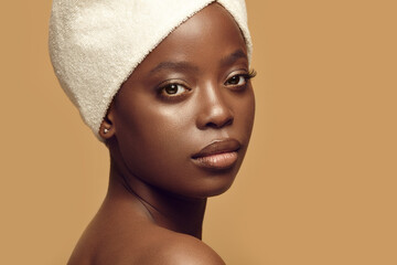 Beautiful African girl in hair drying towel looks to camera.