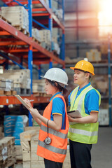 Asian engineer in helmets order and checking goods and supplies on shelves with goods background in warehouse.logistic and business export ,Warehouse worker checking packages on shelf in a large store