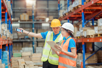 Asian engineer in helmets order and checking goods and supplies on shelves with goods background in warehouse.logistic and business export ,Warehouse worker checking packages on shelf in a large store