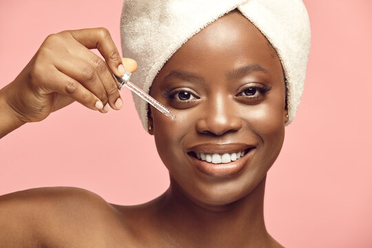 Black Woman In Hair Turban Using Facial Serum, Oil.