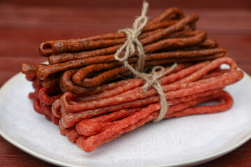 Bundles of delicious kabanosy on wooden table, closeup