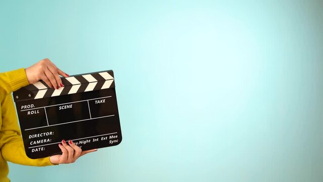 Hand is holding clapper board or clapperboard or movie slate, used in film production and cinema ,movies industry isolated over blue background.