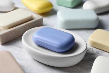 Many different soap bars on white marble table, closeup