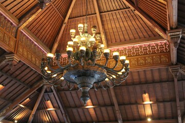 Low angle shot of an old huge chandelier hanging on an ornamented ceiling in Indonesia
