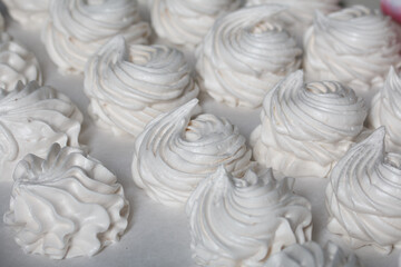 Homemade zephyr. White tray with marshmallows. Stands on black pine boards. Close-up.