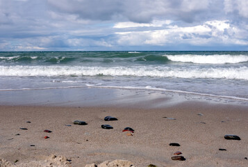 Fototapeta na wymiar Storm weather on Baltic sea, landscape with sand beach with focus on front stones horizontal view