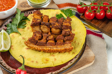 Deep fried pork belly pieces, crispy pork skin appetizer. Tartilla, vegetables and sauce.