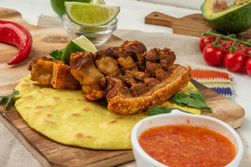 Deep-fried pieces of brisket with crispy skin, chicharones with tartilla and vegetables, and sauce.
