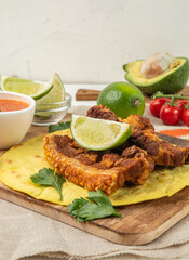 Deep-fried brisket pieces served with tortilla and lime.