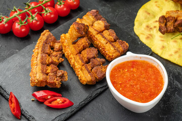 Three pieces of fried brisket with crispy skin on a dark table.