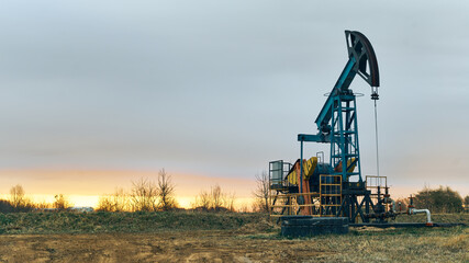 Working oil pumps against a sunset sky. A nodding donkey rig pumps crude up from the ground on an...