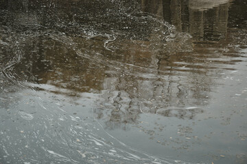autumn maple fallen leaves under lake water surface with waves circles and sky reflation