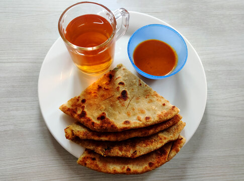 Aloo paratha with black tea,Aloo paratha is a paratha stuffed with potato, originating from the Punjab region of South Asia.